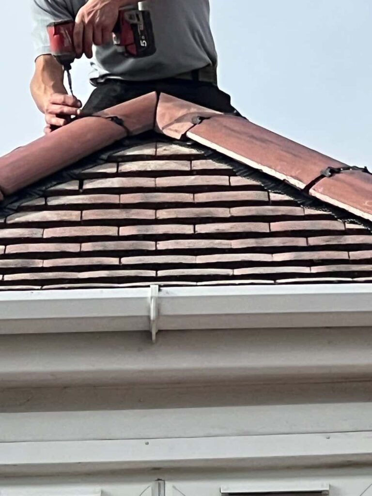 This is a photo of one of the operatives of Downham Market Roofing Repairs installing new ridge tiles